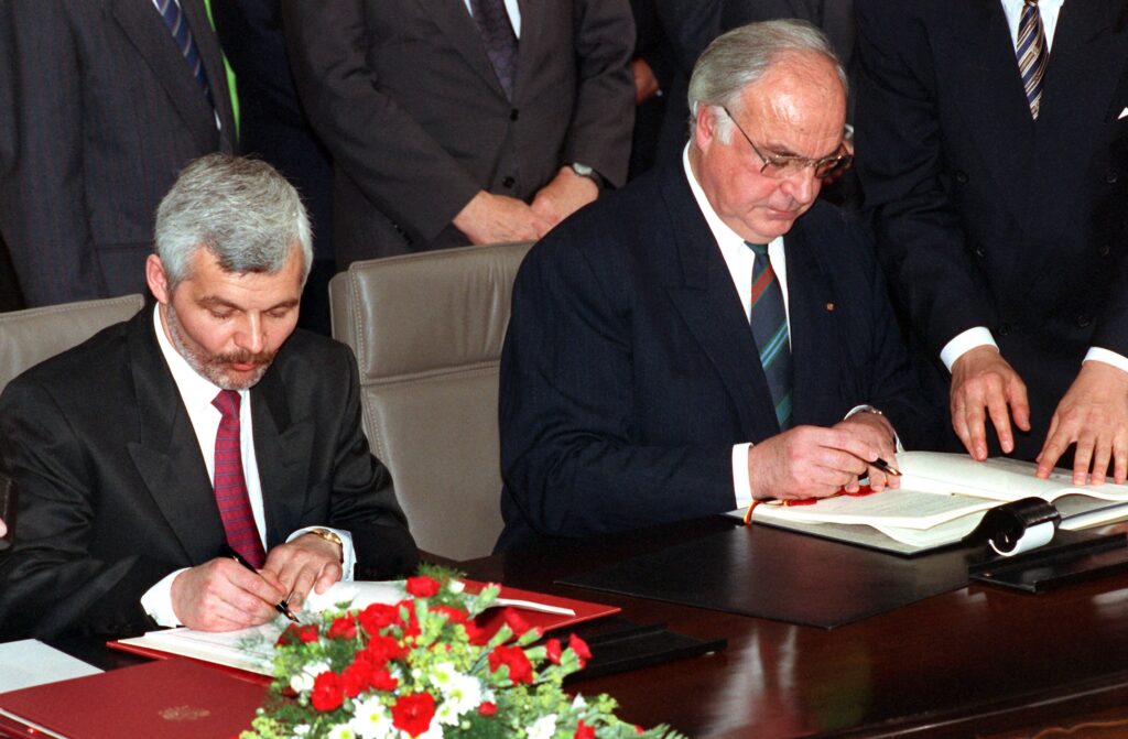 Helmut Kohl i Jan Krzysztof Bielecki siedzą przy stole i podpisują dokumenty