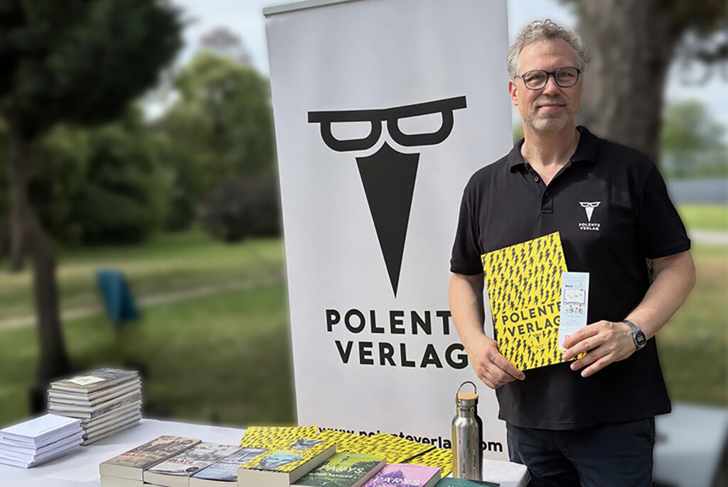 Ein Mann steht an einem Bücherstand.