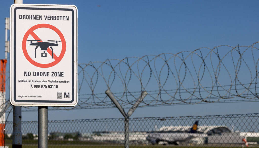 Ein Flughafenzaun mit Stacheldraht und ein Schild, das auf das Drohnenflugverbot hinweist