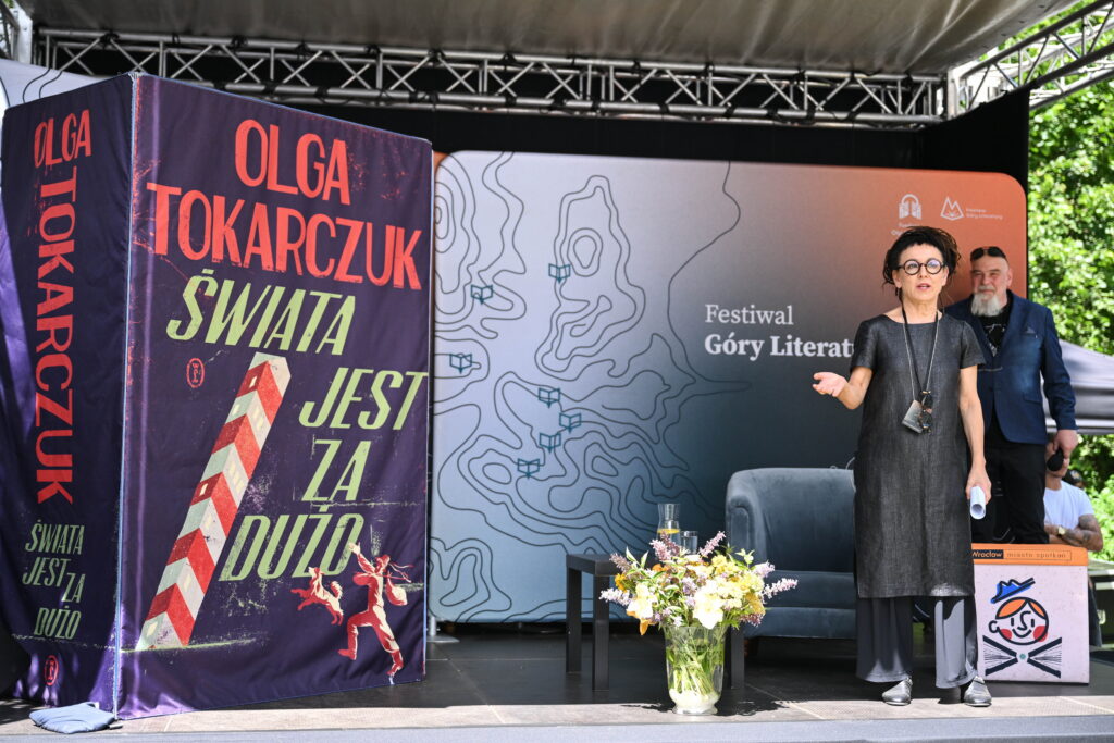 Eine Bühne bei einem Festival mit einem überdimensionalen Buch und den Teilnehmenden der Diskussion. 