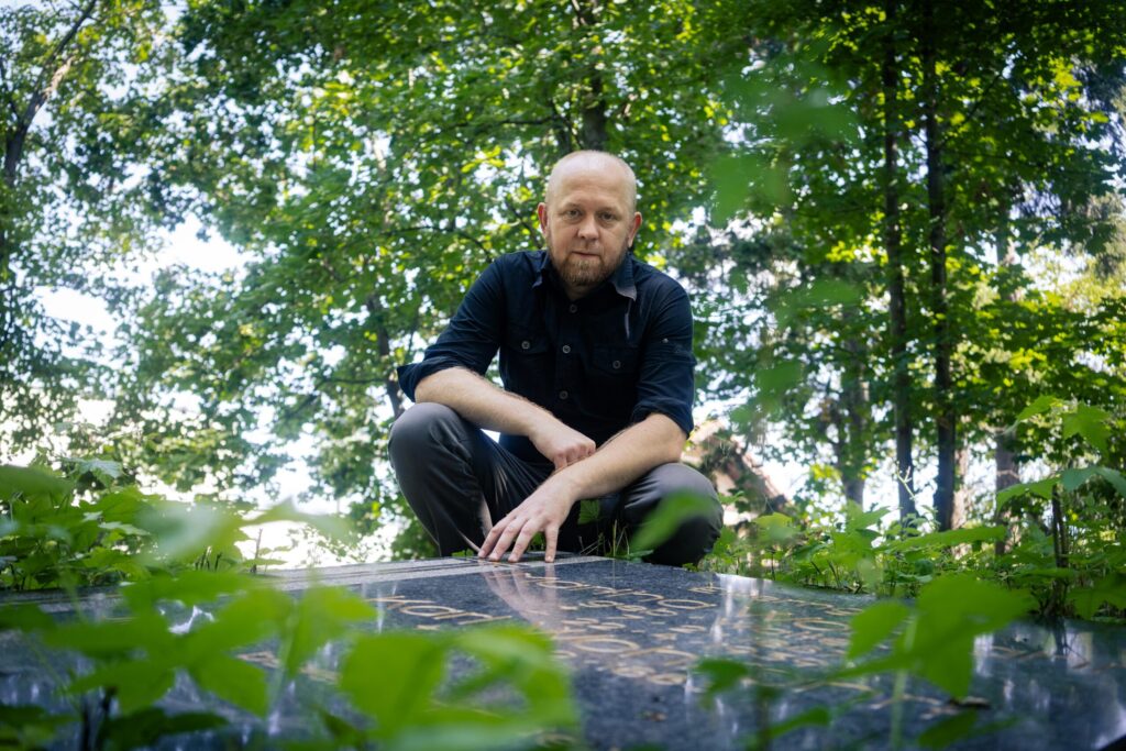 Portret Alana Weissa przed przewróconym nagrobkiem