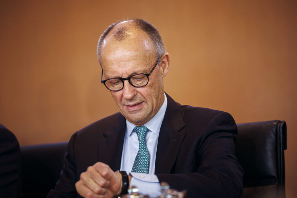 Ein älterer Mann mit Brille schaut auf seine Armbanduhr. 