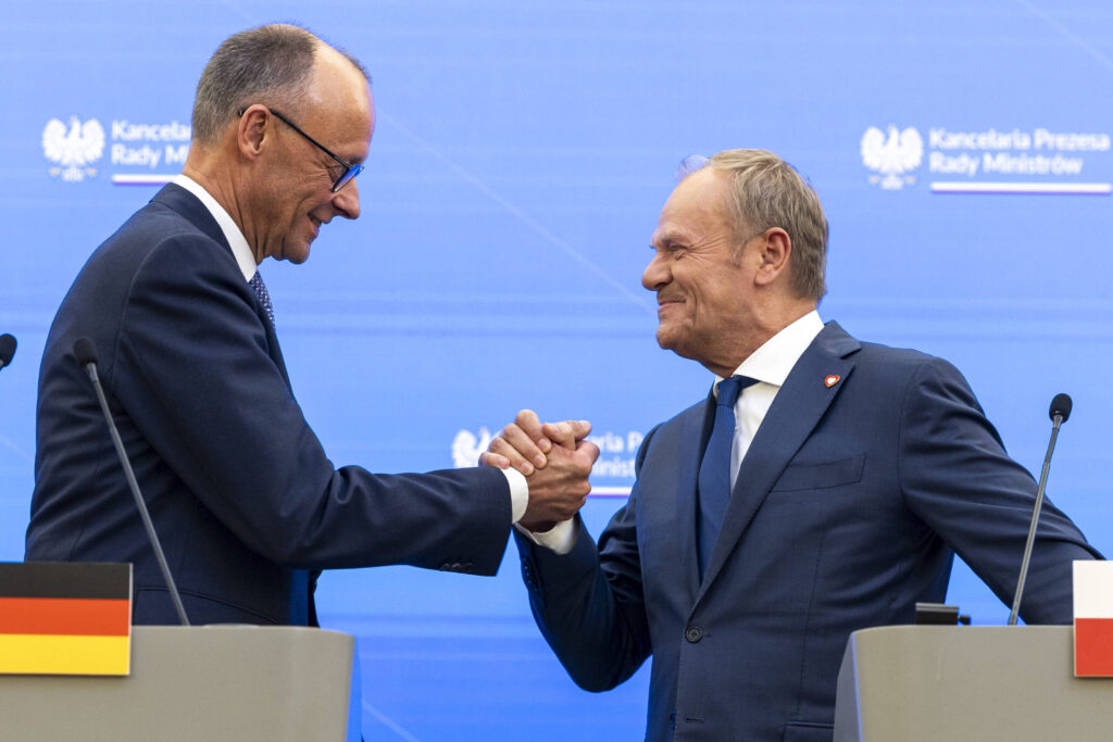 Zwei Männer drücken einander die Hand und lachen vertraut. 