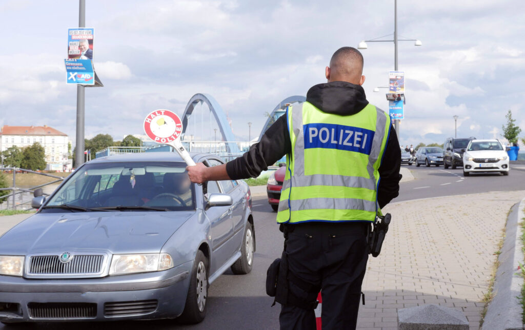 Ein Mann von der Bundespolizei hält einen Wagen für eine Grenzkontrolle an. 