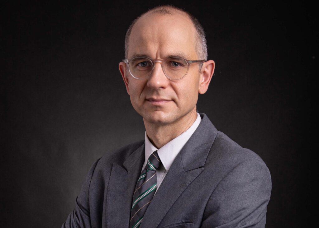 Ein Mann in Anzug und mit Brille blickt in die Kamera