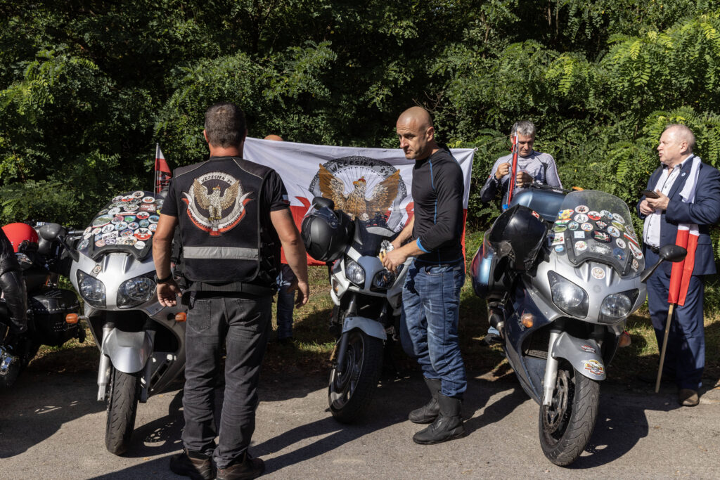 Mehrere Männer stehen an seinen Motorrädern in patriotischer Kleidung.