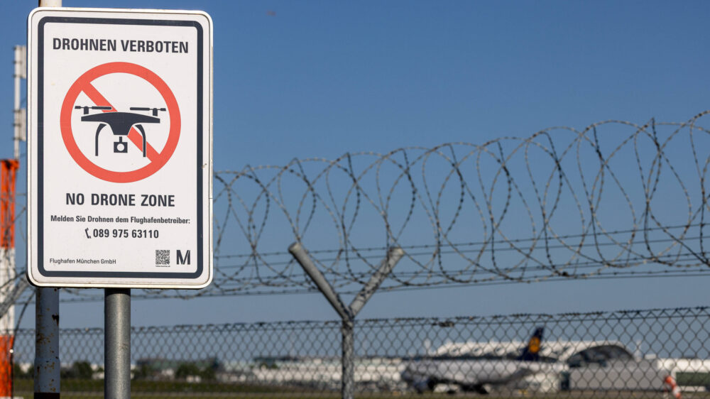Ein Flughafenzaun mit Stacheldraht und ein Schild, das auf das Drohnenflugverbot hinweist