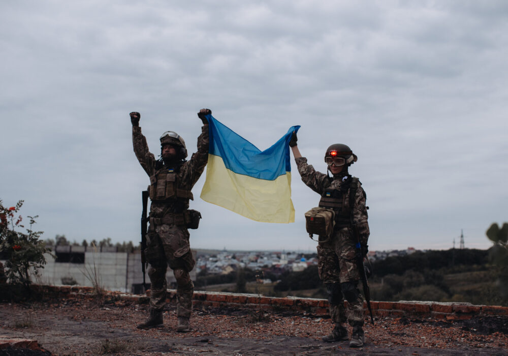 Zwei ukrainische Soldaten halten die ukrainische Flagge hoch