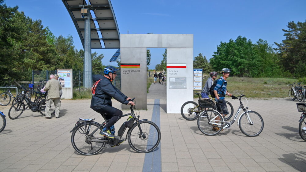 Ludzie na rowerach jadą przez granicę z Niemiec do Polski